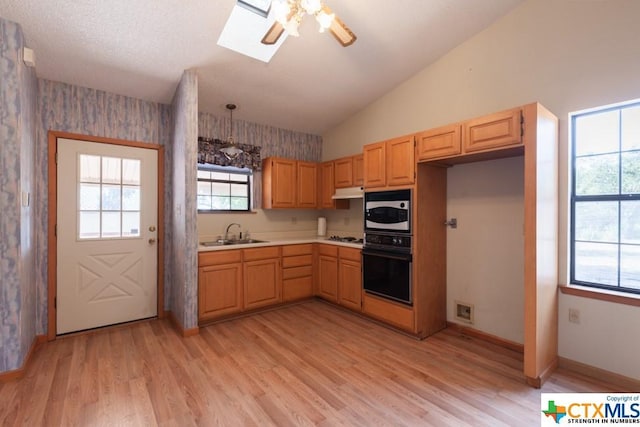 121 S Scenic Loop, Canyon Lake, TX 78133 - kitchen featuring black oven, a skylight, plenty of natural light, light countertops, and wallpapered walls