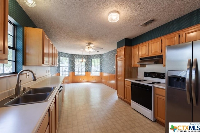 121 S Scenic Loop, Canyon Lake, TX 78133 - kitchen featuring appliances with stainless steel finishes, under cabinet range hood, a sink, light flooring, and wallpapered walls