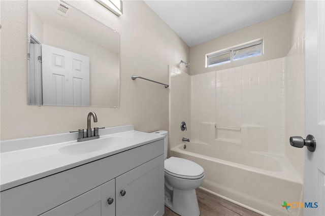 full bathroom featuring visible vents, toilet, vanity, shower / tub combination, and wood finished floors