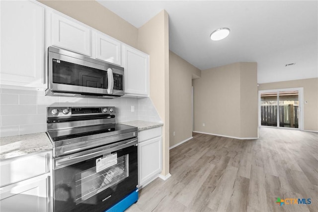 kitchen featuring light stone counters, light wood-style floors, white cabinets, appliances with stainless steel finishes, and backsplash