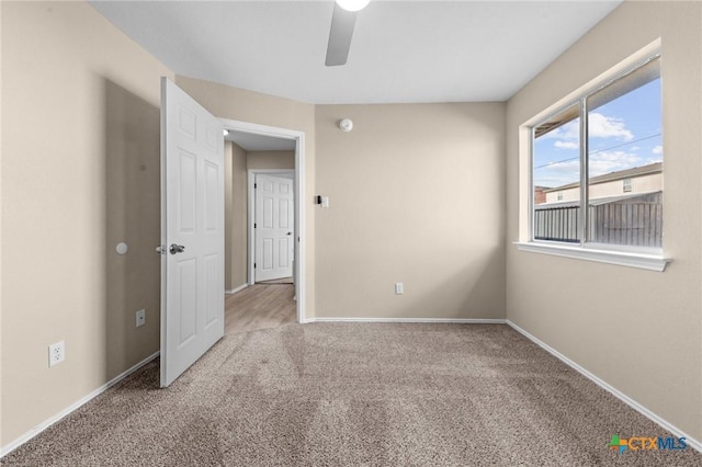 carpeted spare room with ceiling fan and baseboards