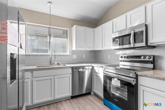 kitchen with appliances with stainless steel finishes, a sink, white cabinetry, and tasteful backsplash