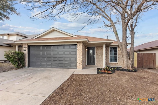 single story home featuring driveway, brick siding, an attached garage, and fence