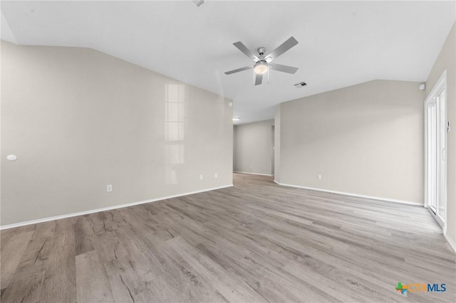 spare room with light wood-style floors, vaulted ceiling, and a ceiling fan