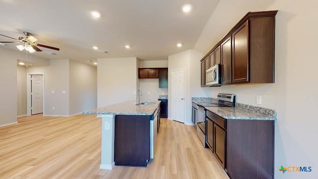 kitchen with a center island with sink, sink, light hardwood / wood-style flooring, light stone counters, and stainless steel appliances