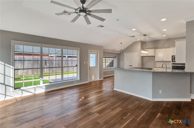 105 Legend Dr, Victoria, TX 77904 - kitchen featuring lofted ceiling, light stone counters, white cabinets, decorative backsplash, and dark wood-style floors