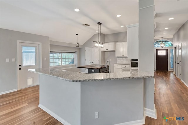 105 Legend Dr, Victoria, TX 77904 - kitchen featuring stainless steel oven, lofted ceiling, white cabinets, light wood-type flooring, and baseboards