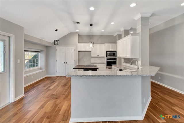 105 Legend Dr, Victoria, TX 77904 - kitchen with appliances with stainless steel finishes, white cabinetry, light stone counters, a peninsula, and tasteful backsplash