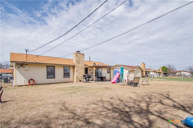 back of house with a patio, fence, a lawn, and a chimney