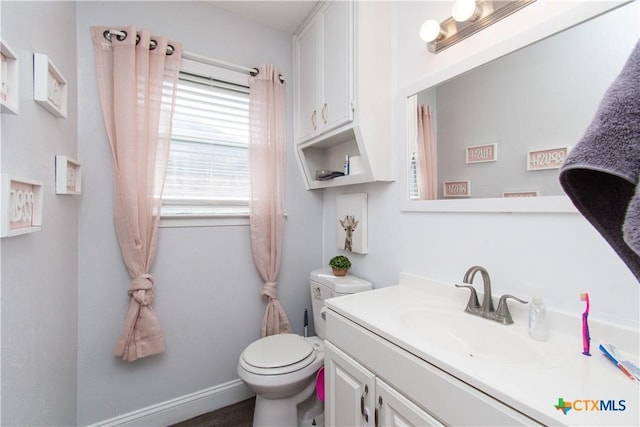 half bathroom with baseboards, toilet, and vanity