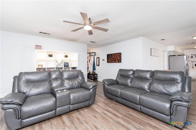 living room featuring visible vents, light wood-type flooring, and ceiling fan