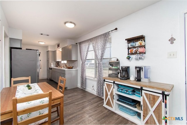 kitchen with visible vents, gray cabinetry, dark wood-style floors, freestanding refrigerator, and light countertops