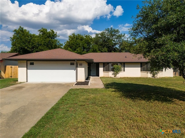 ranch-style home with an attached garage, a front lawn, concrete driveway, and brick siding