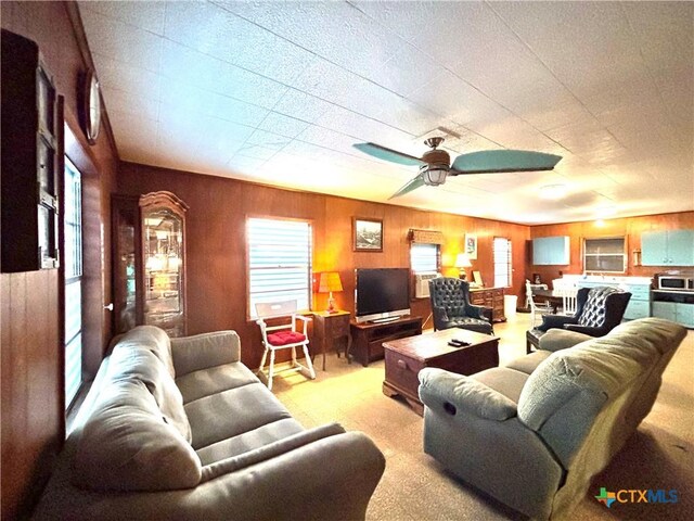 living room featuring ceiling fan and wood walls