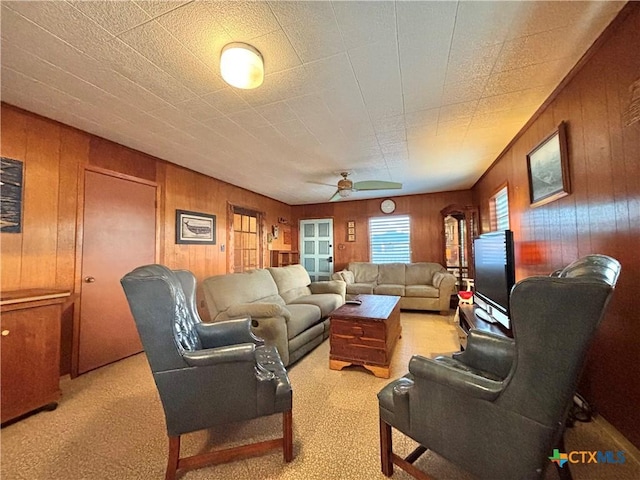 carpeted living room with wood walls and ceiling fan