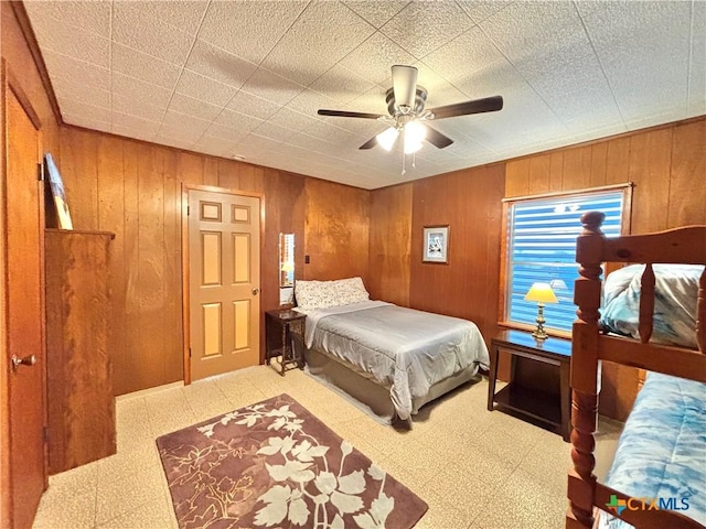 bedroom featuring ceiling fan and wooden walls