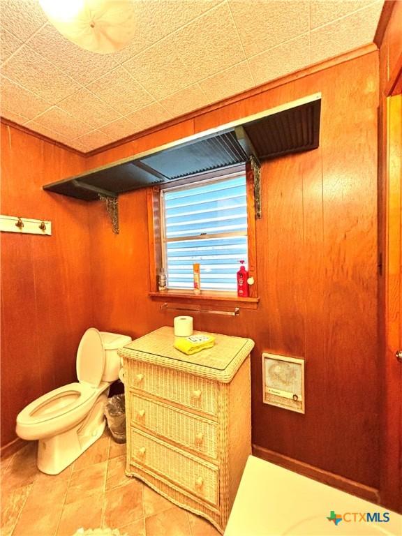 bathroom featuring toilet and wood walls