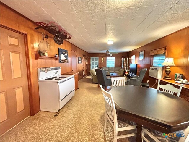 dining area with ceiling fan, cooling unit, and wood walls