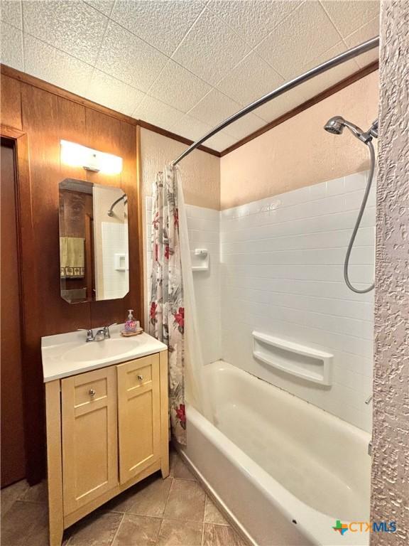 bathroom with wooden walls, vanity, and shower / tub combo