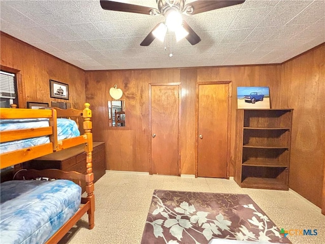 bedroom with wood walls and ceiling fan