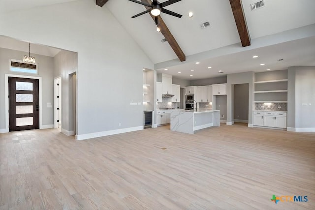 unfurnished living room featuring ceiling fan, beamed ceiling, high vaulted ceiling, and light hardwood / wood-style floors