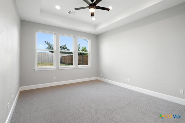 carpeted empty room with a tray ceiling and ceiling fan