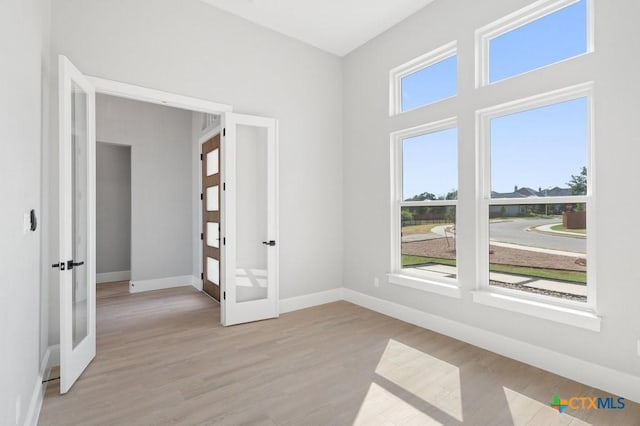 empty room with light hardwood / wood-style floors and french doors