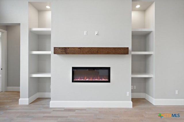 unfurnished living room featuring built in features and light wood-type flooring