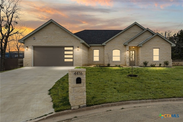 view of front of property with concrete driveway, a front lawn, an attached garage, and a shingled roof