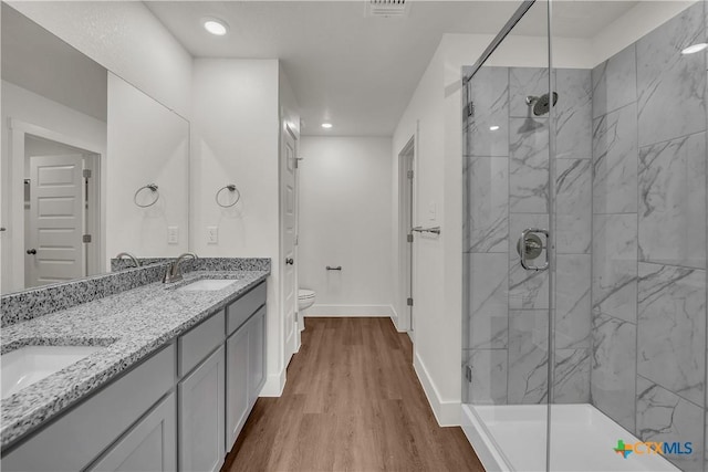 bathroom with vanity, toilet, a shower with shower door, and hardwood / wood-style floors