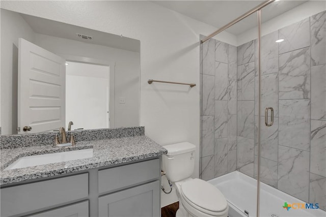 bathroom with a shower with door, vanity, and toilet