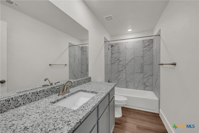 full bathroom with hardwood / wood-style flooring, vanity, toilet, and tiled shower / bath combo