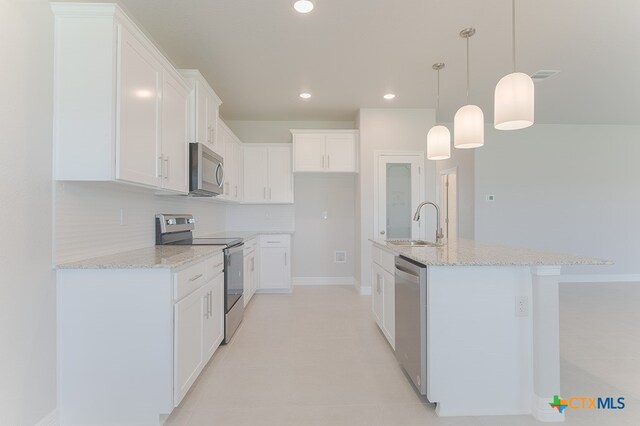 kitchen with pendant lighting, white cabinets, a kitchen island with sink, and stainless steel appliances