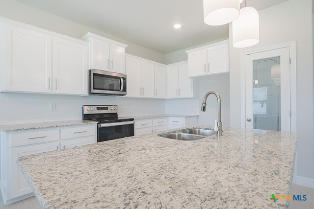 kitchen with stainless steel appliances, white cabinets, sink, backsplash, and pendant lighting