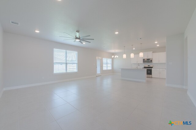 unfurnished living room with light tile patterned flooring, ceiling fan with notable chandelier, and sink