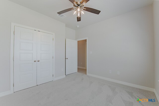 unfurnished bedroom featuring light colored carpet, ceiling fan, and a closet