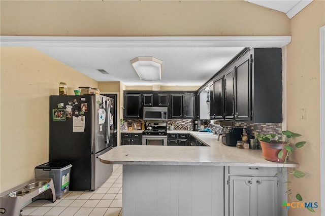 203 Yorkshire Ln, Victoria, TX 77904 - kitchen with stainless steel appliances, dark cabinetry, a peninsula, light countertops, and tasteful backsplash