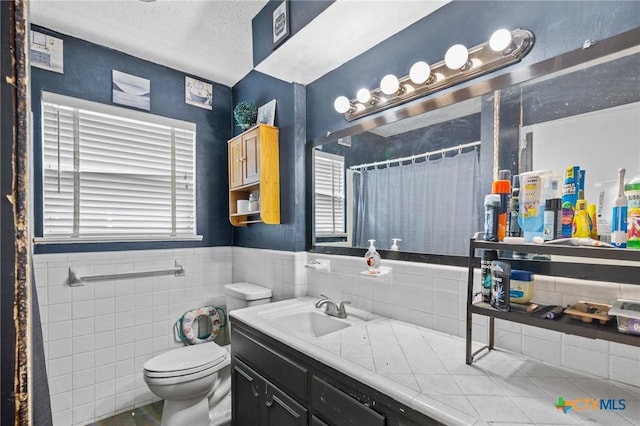 203 Yorkshire Ln, Victoria, TX 77904 - full bathroom with vanity, healthy amount of natural light, a textured ceiling, curtained shower, and a wainscoted wall