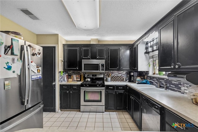 203 Yorkshire Ln, Victoria, TX 77904 - kitchen featuring appliances with stainless steel finishes, dark cabinets, light countertops, a textured ceiling, and backsplash