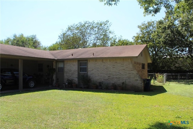 view of property exterior with brick siding, a lawn, a gate, and fence