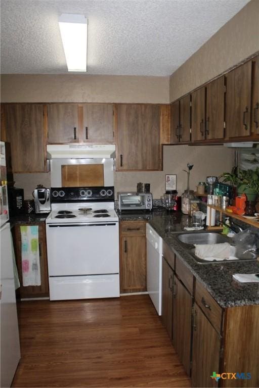 kitchen with dark wood-type flooring, a sink, under cabinet range hood, a textured ceiling, and white appliances