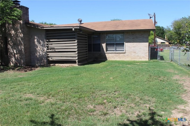 rear view of house featuring a gate, fence, a yard, a chimney, and brick siding