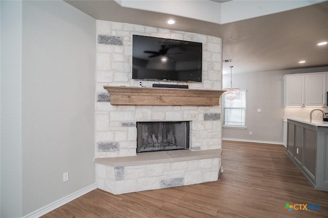 unfurnished living room with visible vents, baseboards, dark wood finished floors, a fireplace, and a sink