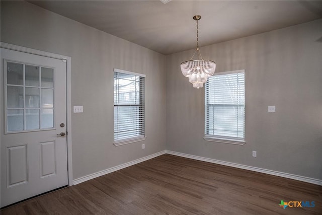 foyer featuring baseboards, dark wood-style flooring, a wealth of natural light, and a chandelier