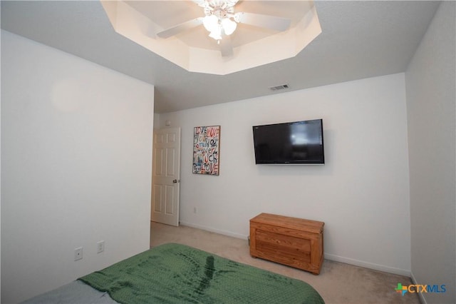 bedroom featuring baseboards, visible vents, a raised ceiling, and light colored carpet