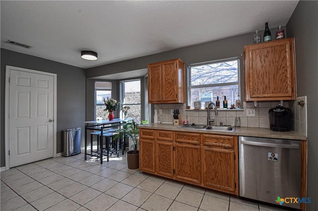 kitchen featuring light countertops, visible vents, backsplash, stainless steel dishwasher, and a sink