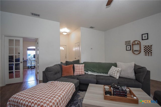 living room featuring dark wood-type flooring, visible vents, and a ceiling fan