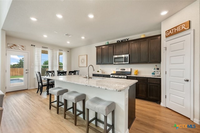 3301 Amerigo Pl, Round Rock, TX 78665 - kitchen with appliances with stainless steel finishes, a sink, a kitchen bar, a center island with sink, and dark brown cabinetry