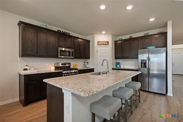 3301 Amerigo Pl, Round Rock, TX 78665 - kitchen featuring stainless steel appliances, a sink, light wood-style flooring, dark brown cabinetry, and recessed lighting