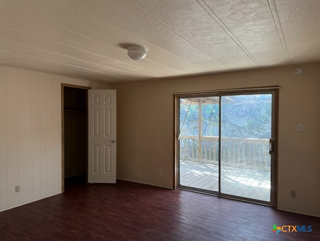 empty room with a textured ceiling and dark hardwood / wood-style flooring